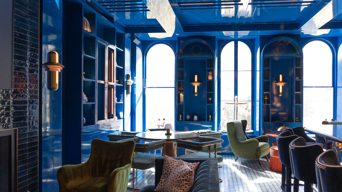 Glossy blue lounge at Jupiter Supper Club with arched built-in shelving and arched windows