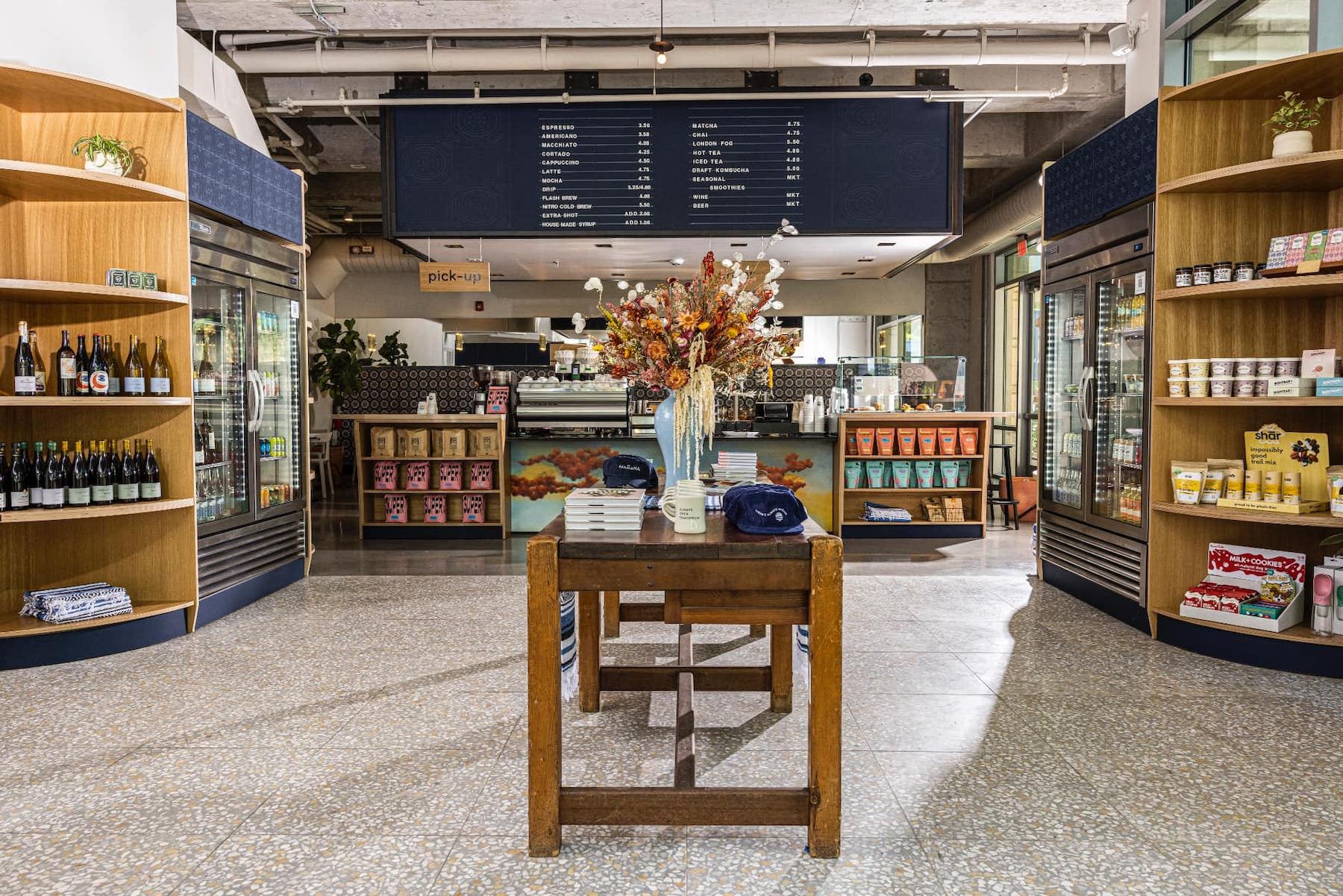 Coffee shop with curved wood shelving and a mural-fronted counter at Mañana Dos